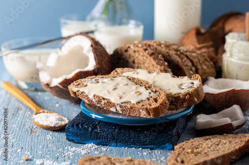 Coconut butter cream spread on slices of whole wheat bread with fresh coconut and flakes.