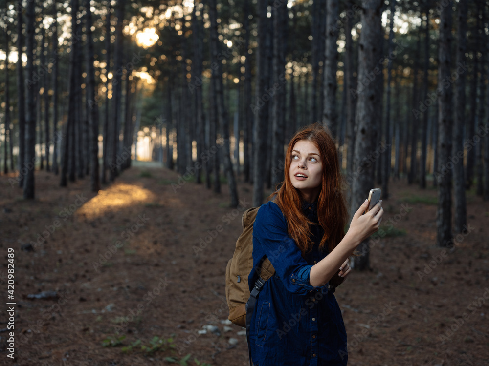 Happy woman in pine forest with mobile phone navigator tourism model