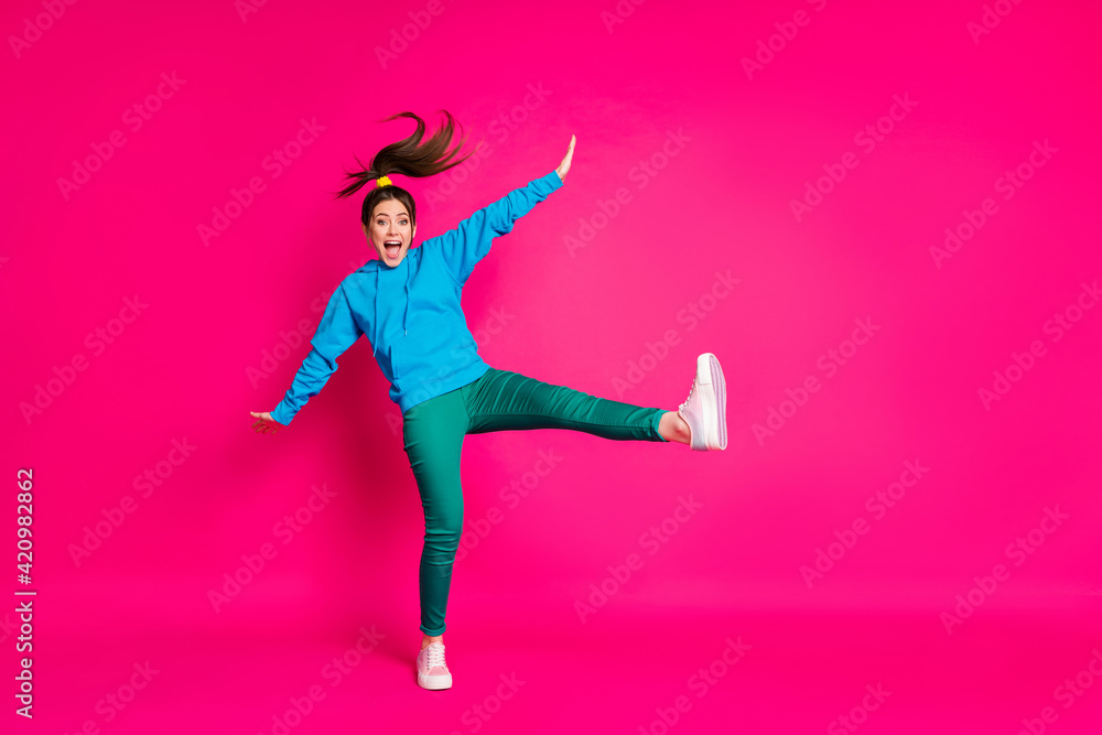 Full length photo of funny excited young lady wear blue sweater dancing standing one leg isolated bright pink color background