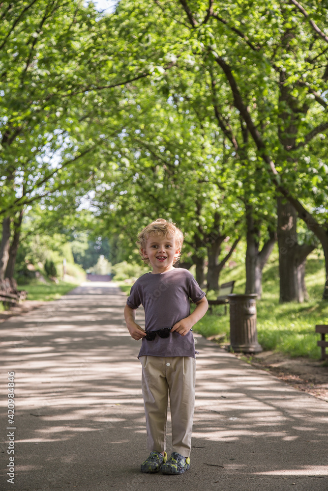 A walk in the park of a curly-haired boy. Sunny weather, the park is all in multi-colored colors A walk in the park of a curly-haired boy. Sunny weather, the park is all in multi-colored colors
