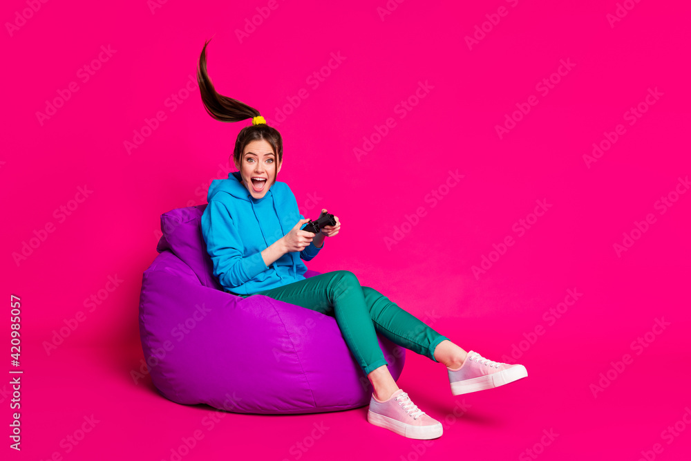 Full length photo of excited woman dressed blue hoodie rest purple bean bag  holding playstation isolated pink color background Stock Photo | Adobe Stock