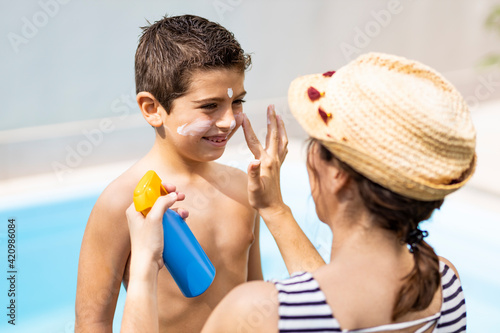 Mother aplying sunscreen to her son on a summer day photo
