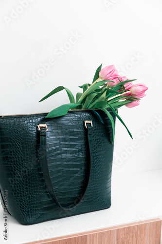 Red tulips from the Netherlands in a green ladies bag. Office work in spring. Spring mood while shopping	 photo