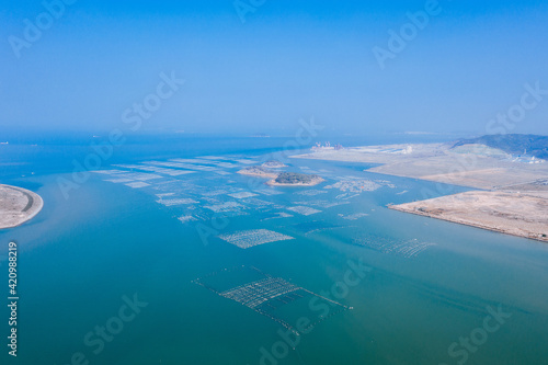 Aerial view of ocean, coastline and marine farms in Fujian, China, against blue sky