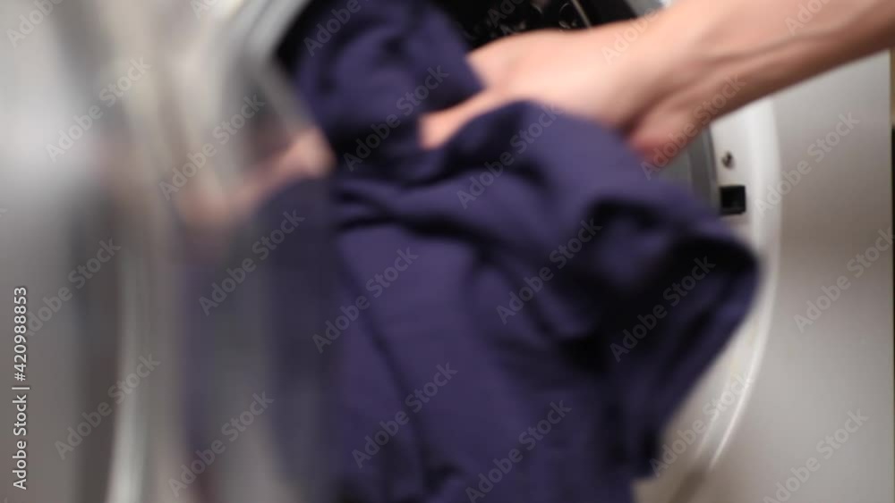 Hand puts linen Inside washing machine Hand puts linen Inside washing machine