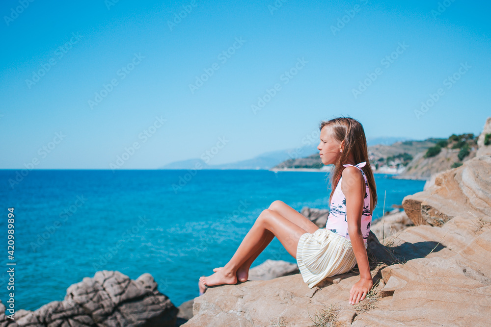 Little girl outdoor on edge of cliff seashore
