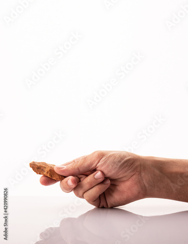 a man holds an Atherian spearhead. the material is quartzite. Dating from the Stone Age and the Paleolithic period. From the Acheulean culture found in the Sahara desert. White background. technology photo