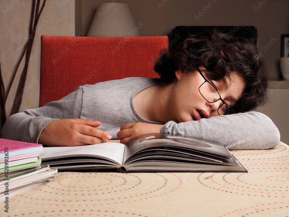 black-haired Caucasian boy, has fallen asleep while studying for exams, at home black-haired Caucasian boy, has fallen asleep while studying for exams, at home