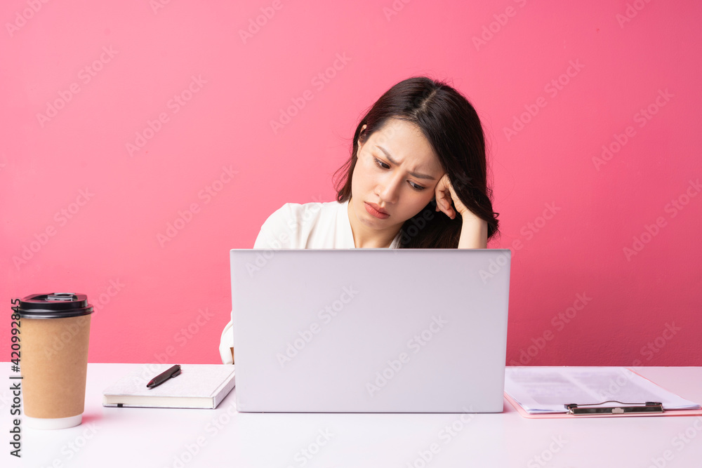 Young Asian businesswoman sitting working with expression on background Young Asian businesswoman sitting working with expression on background