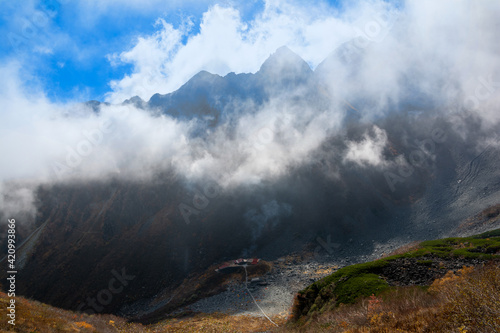 松本市安曇の標高2,300mの日本最大規模の氷河圏谷、涸沢カールのテント場、涸沢ヒュッテ。雲に隠れる前穂高岳。北穂高岳より。ガス、もや。