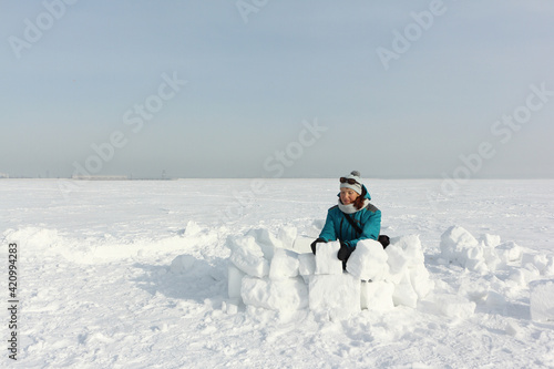 Happy woman building an igloo on the snow
