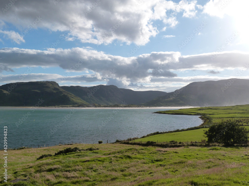 sunny irish landscape with ocean and mountains and green fields