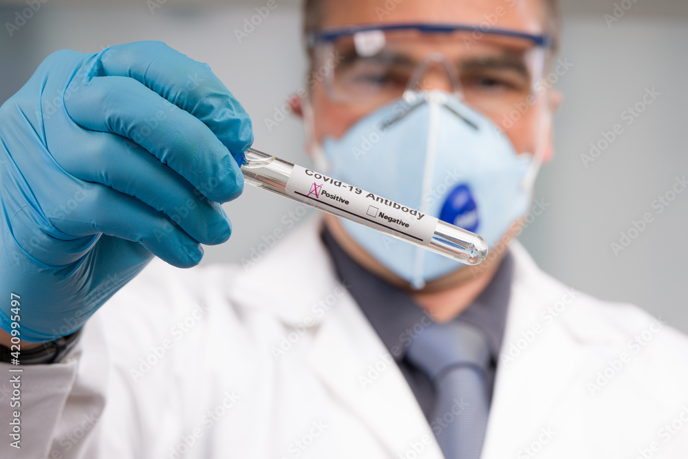 Doctor with medical face mask and medical gloves is handling a positive corona antibody test Doctor with medical face mask and medical gloves is handling a positive corona antibody test