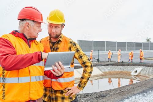 Zwei Bauarbeiter mit Tablet PC kontrollieren Baustelle