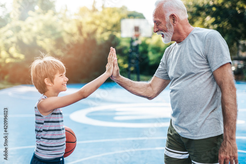 Grandfather and his grandson enjoying together on basketball court.