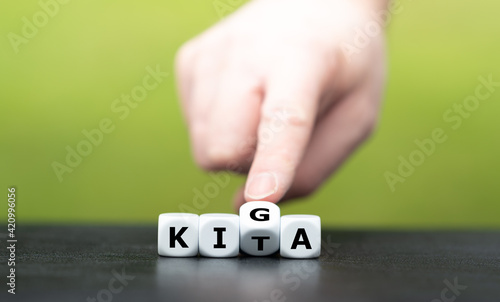 Hand dreht Würfel und ändert die Abkürzung KITA (Kindertagesstätte) in KIGA (Kindergarten).