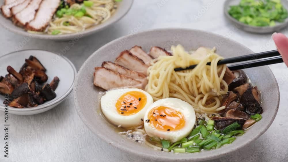 Ramen, asian noodles with pork, egg and shiitake mushrooms. Eating noodle soup with wooden chopsticks Ramen, asian noodles with pork, egg and shiitake mushrooms. Eating noodle soup with wooden chopsticks