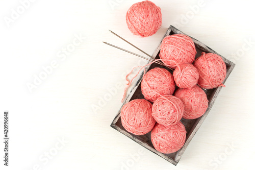 Skeins of pink yarn in a wooden box on a light background. Female needlework concept. Flat lay. photo