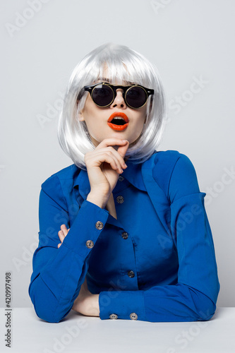attractive woman in white wig sunglasses red lips glamor blue shirt isolated background © SHOTPRIME STUDIO