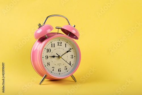 A table clock with a yellow background flat lay shot.