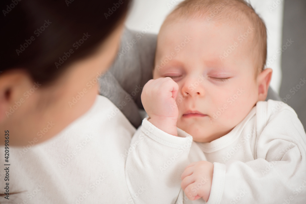 Young mother holding her newborn child. Mom nursing baby. Woman and new born boy relax in a white bedroom. Young mother holding her newborn child. Mom nursing baby. Woman and new born boy relax in a white bedroom.