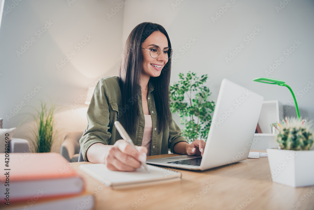 Portrait of charming cheerful girl working remotely making notes developing e-commerce at home house flat indoor Portrait of charming cheerful girl working remotely making notes developing e-commerce at home house flat indoor