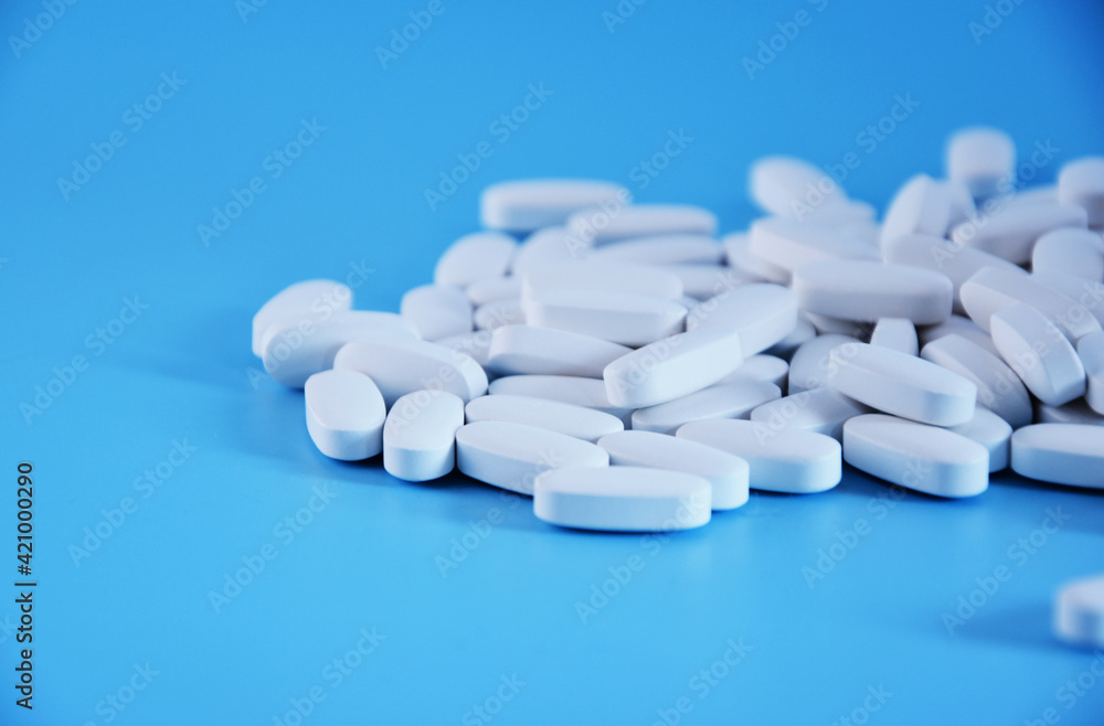 White pills on blue background. Medical tablets, macro view. White pills on blue background. Medical tablets, macro view.