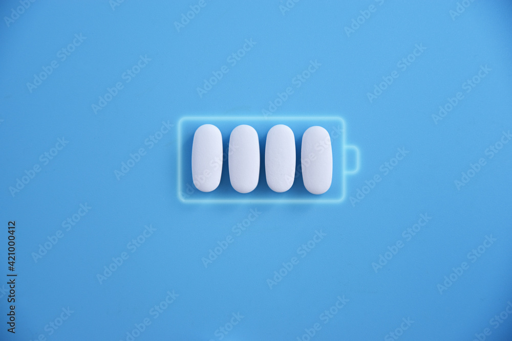 Obraz premium Battery and white pill medicine, energy for life, idea Battery charging symbol and capsules. Health and Technology, energy for life.