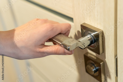 Woman's hand holds on to the metal handle of a milk door close-up