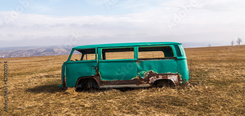 lateral view of an Rusty old minibus van abandoned on a field