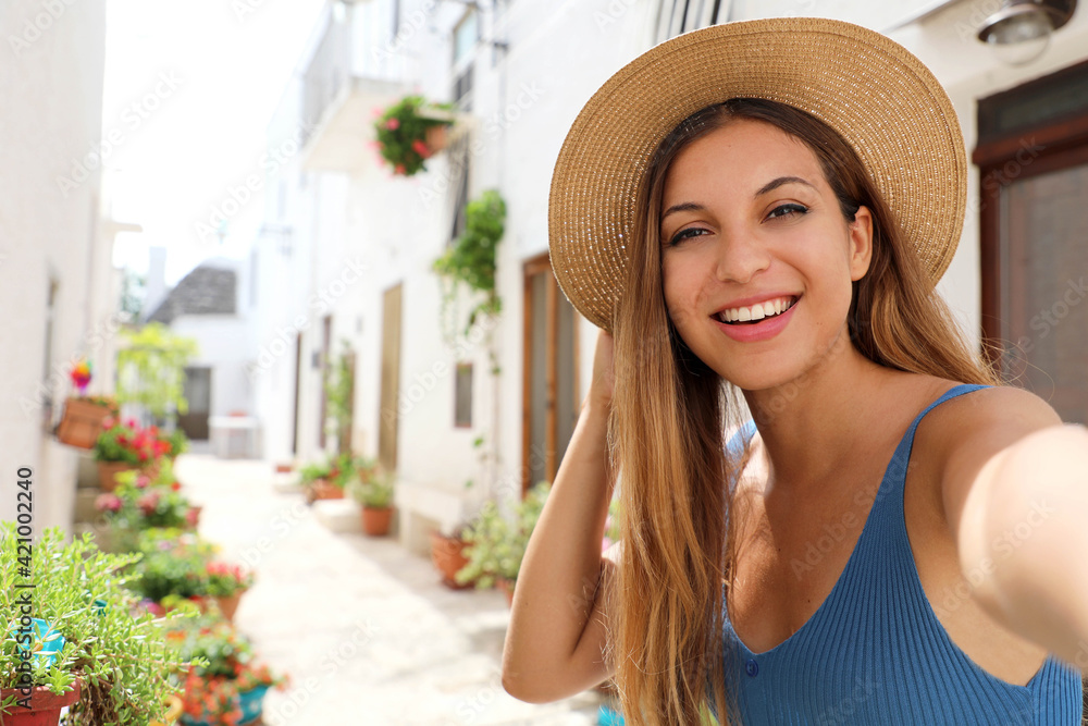 Attractive smiling tourist girl take self portrait in cozy village of southern Europe
