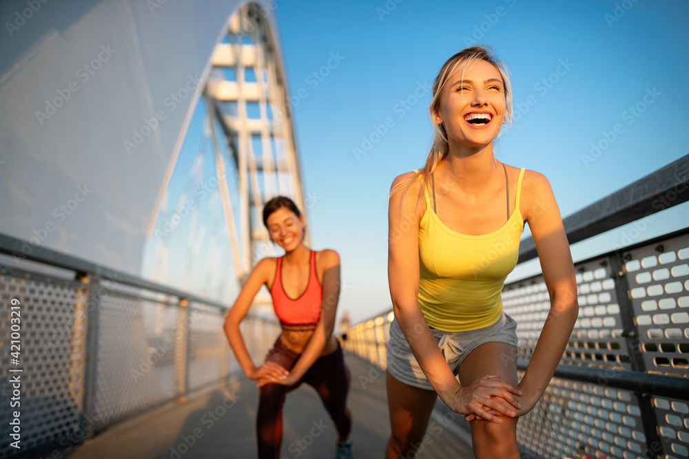 Beautiful happy women friends working out, exercising, running, jogging outdoor.