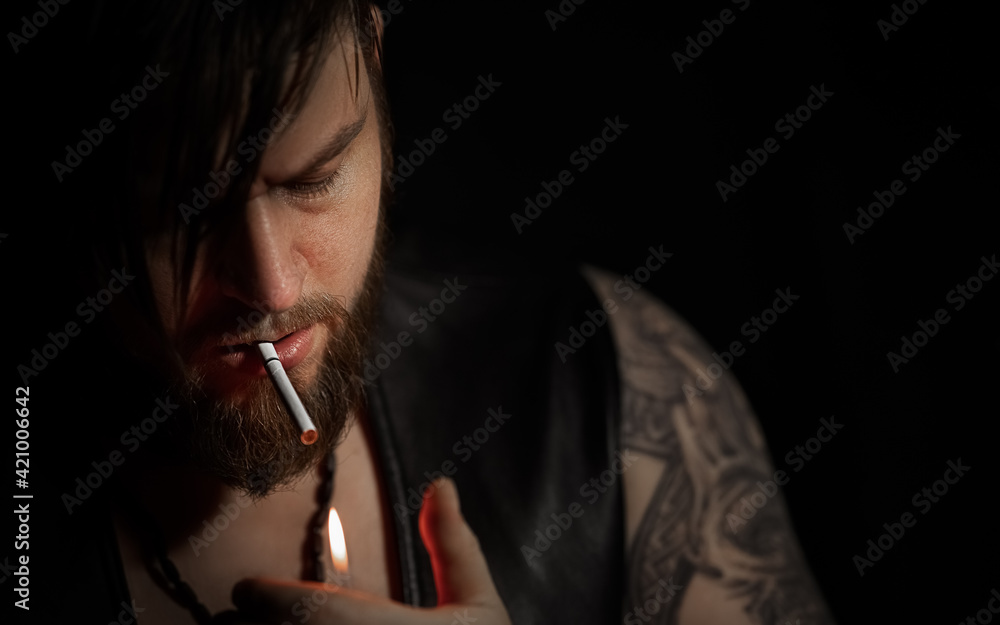 Obraz premium Brutal bearded man with a cigarette in a recording Studio with guitar on the black background