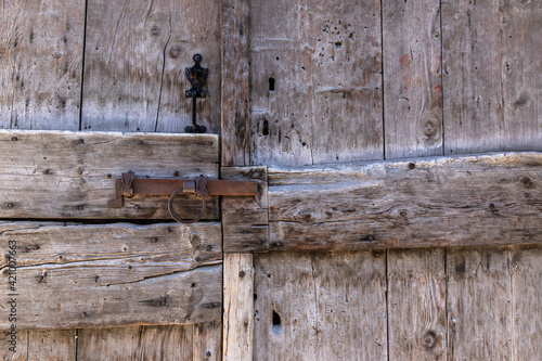 old wooden door with steel locking lever in a small isolated village in the French Alps