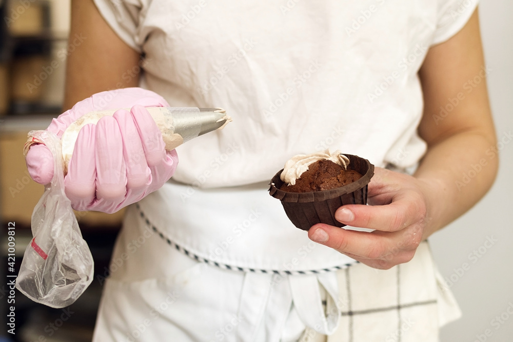 Pastry chef applies cream to chocolate muffin Pastry chef applies cream to chocolate muffin