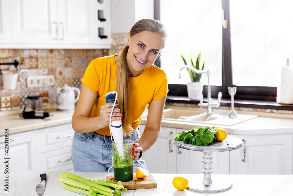 A young woman with a blender and green vegetables making a detox cocktail. Healthy food, cooking, vegetarian food, diet A young woman with a blender and green vegetables making a detox cocktail. Healthy food, cooking, vegetarian food, diet