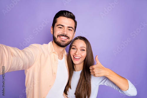 Photo of brunette trendy stylish couple make thumb up take selfie camera charming smile isolated on violet color background