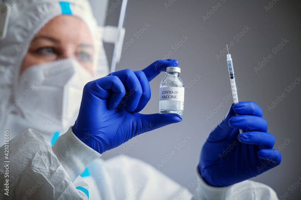 Detail closeup of syringe needle and ampoule , nurse taking injection shot,hands in blue protective gloves holding vaccination equipment,immunization against Corona virus,COVID-19 Detail closeup of syringe needle and ampoule , nurse taking injection shot,hands in blue protective gloves holding vaccination equipment,immunization against Corona virus,COVID-19