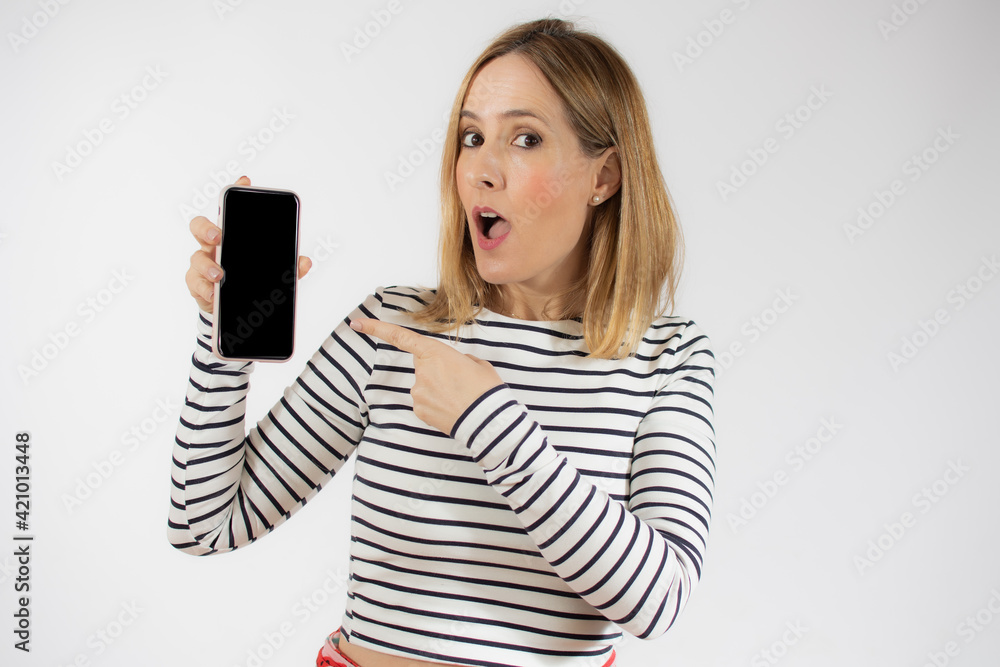 Portrait of a smiling young woman showing blank screen mobile phone while standing isolated over white background Portrait of a smiling young woman showing blank screen mobile phone while standing isolated over white background