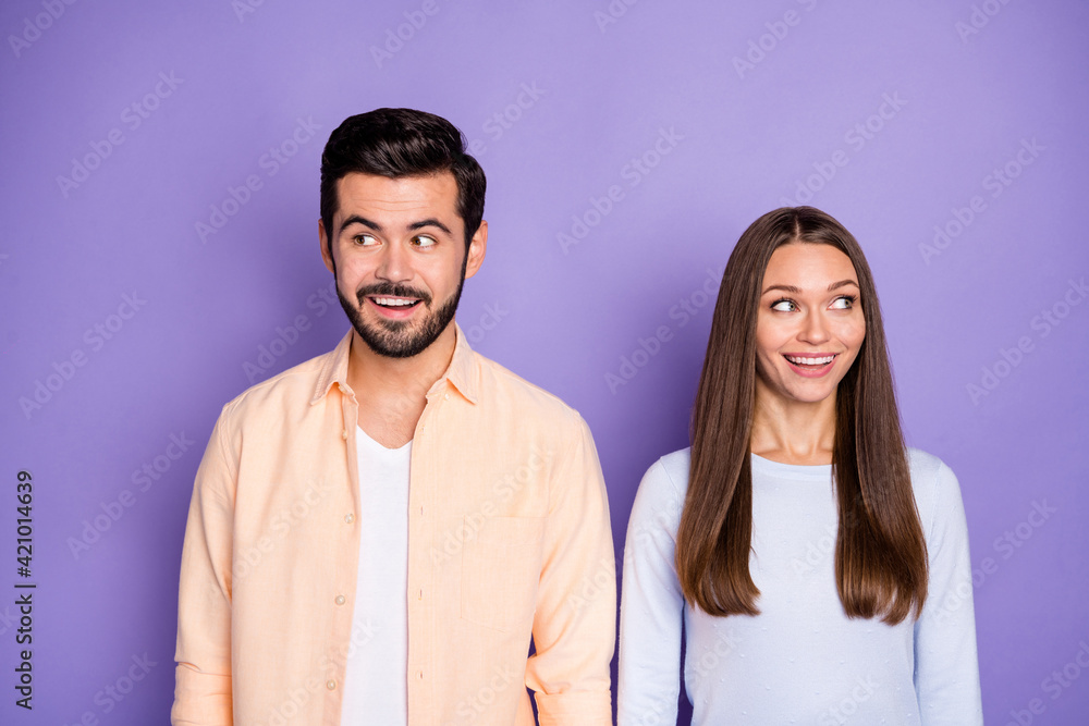 Photo of cheerful couple wear blue sweater orange shirt look copyspace amazed isolated on purple color background