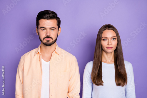Portrait of two persons stand together look camera no emotions face isolated on purple color background
