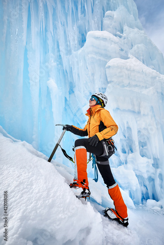 Woman climbing frozen waterfall in the mountains