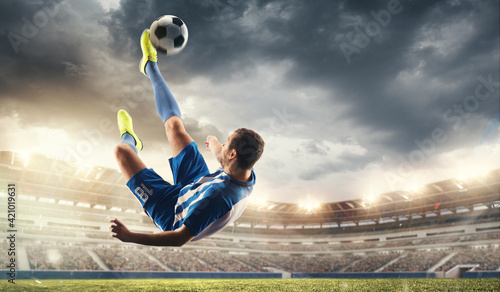 Male football or soccer player at stadium in flashlight. Young male sportive model training. Moment of attacking, catching. Concept of sport, competition, winning, action, motion, overcoming. Flyer. photo