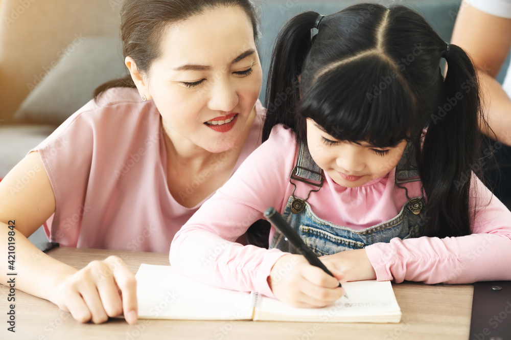 Asian mother helping daughter with homework at living room. Asian mother helping daughter with homework at living room.