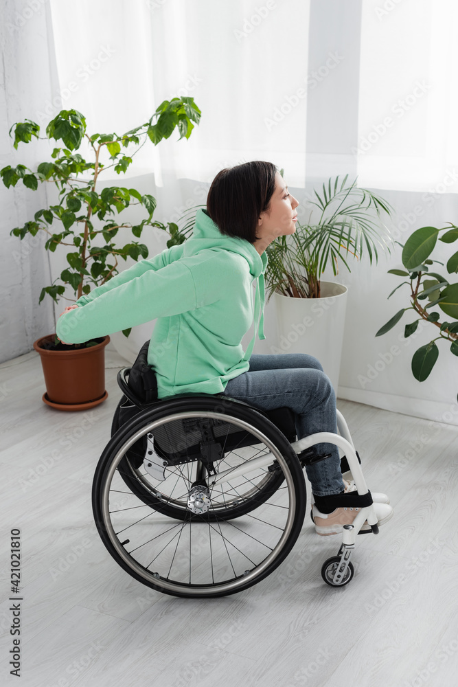 Side view of handicapped woman in wheelchair training in living room Side view of handicapped woman in wheelchair training in living room