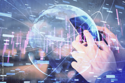 Double exposure of man's hands holding and using a digital device and forex graph drawing. Financial market concept.