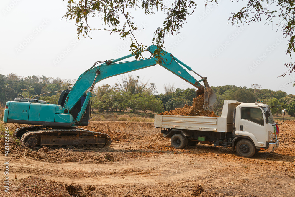 Cyan excavator digging the soil into a truck ,In the construction site area Cyan excavator digging the soil into a truck ,In the construction site area