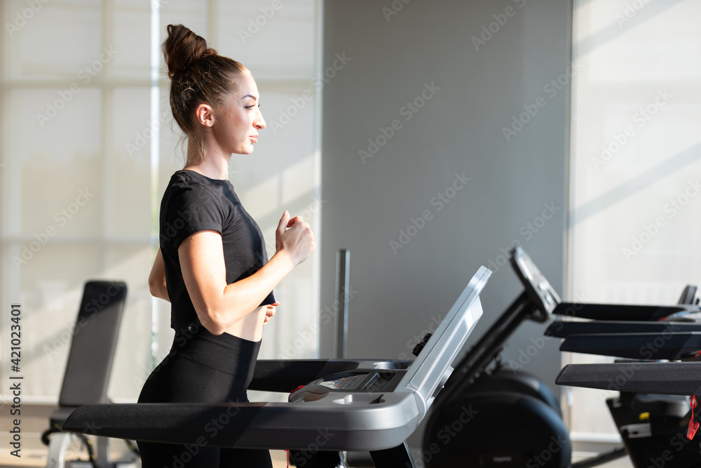 young sports woman working out and running on treadmill in gym young sports woman working out and running on treadmill in gym