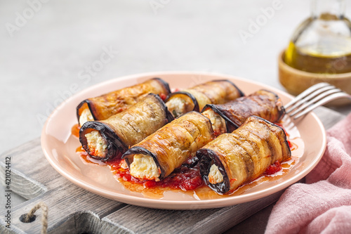 Eggplant roll ups with ricotta, parmesan cheese and tomato sauce. Light background.