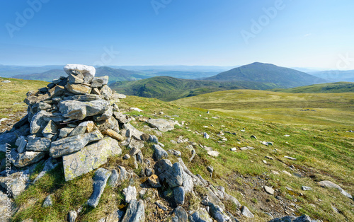 A pile of stones marking the mountain top of Meall a Bharr with the summit of Schiehallion in the distance in the Scottish Highlands, UK landscapes. © Duncan Andison